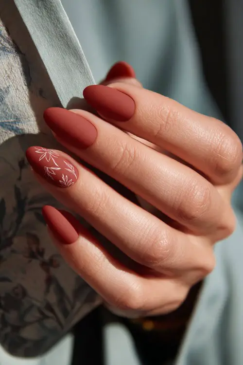 Matte terracotta nails with delicate floral line art, bridesmaid holding a wedding program booklet 