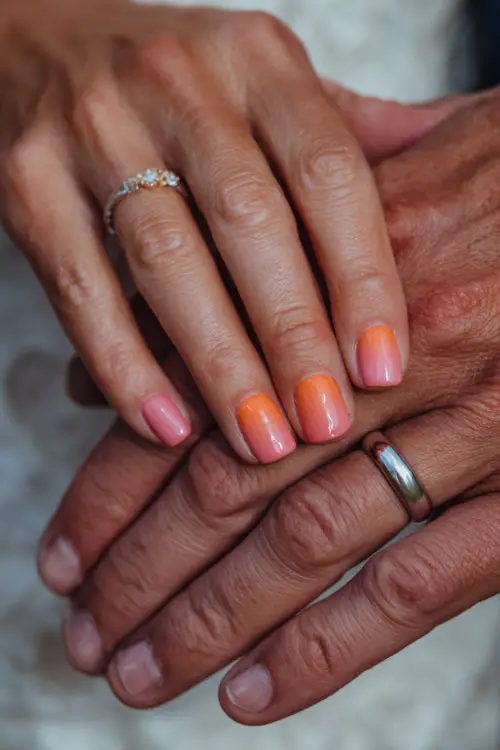 Ombré nails blending burnt orange and pale peach shades, bride’s hands intertwined with groom’s, wedding ring in focus