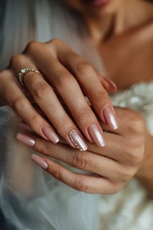 Rose gold chrome nails with fine rhinestone details, bride’s hands adjusting a sheer bridal veil 