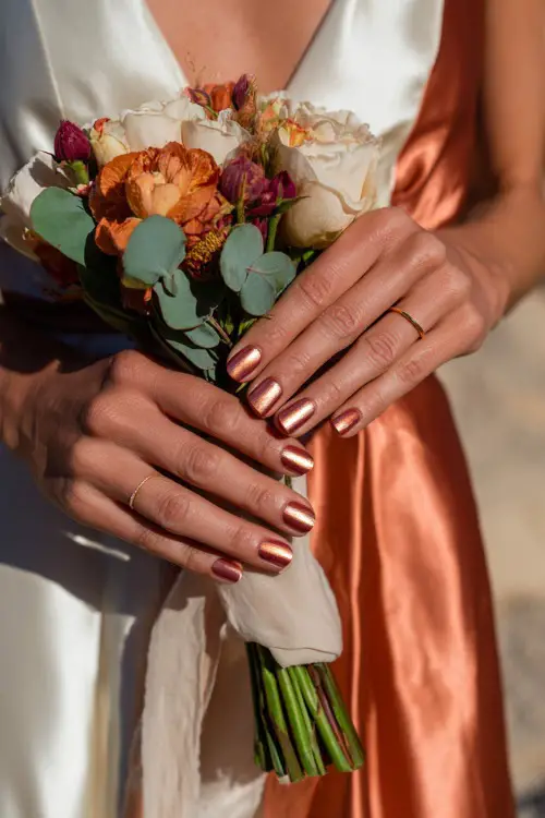 Rust and cream ombré nails with metallic copper foil highlights, bridesmaid’s hands adjusting a silk ribbon bouquet 