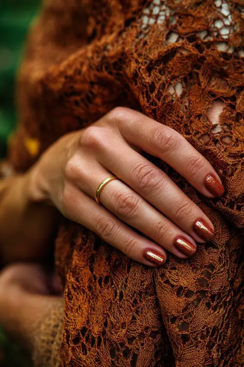 Short rust nails with gold striping accents, bridesmaid’s hand resting on a lace shawl in autumn background