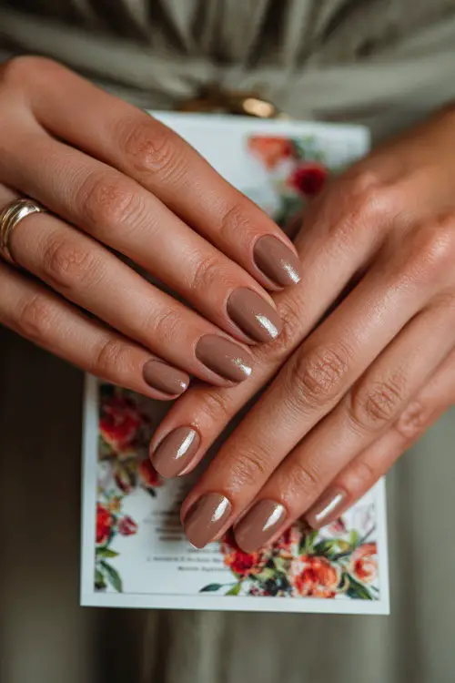 Warm brown nails with subtle glitter gradient, guest holding a wedding menu card decorated with floral prints 