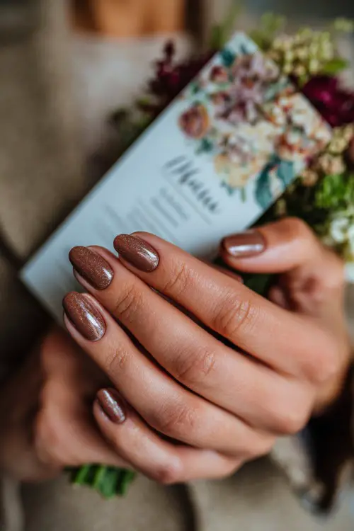 Warm brown nails with subtle glitter gradient, guest holding a wedding menu card decorated with floral prints
