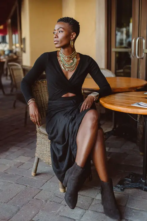 A Black woman wears a modern boho outfit combining a flowy wrap skirt, a fitted knit top, ankle boots, and bold jewelry, styled in a stylish outdoor café environment 