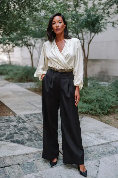A woman over 30 wears a polished boho chic look with wide-leg pants, a tucked-in blouse with draped details, pointed-toe heels, and a statement belt 