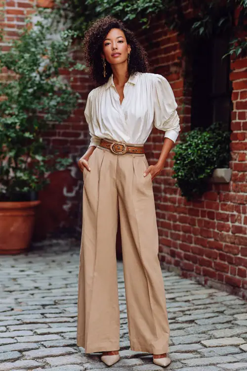 A woman over 30 wears a polished boho chic look with wide-leg pants, a tucked-in blouse with draped details, pointed-toe heels, and a statement belt