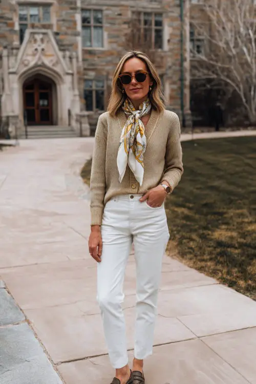 A woman over 40 wears a classic cardigan with a printed scarf, straight jeans, loafers, posing in a university courtyard, full-body fashion photography 