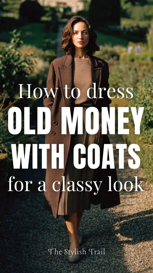 A woman over 40 wears an old money with a coat layered over a pleated midi skirt, cashmere sweater, and low heels, photographed in a countryside estate garden