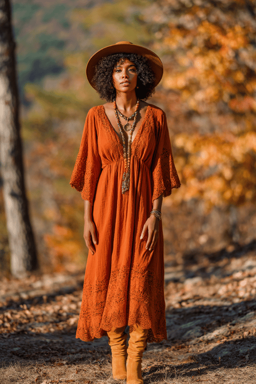 a beautiful Black woman with natural coily afro hair wearing a flowing rust-orange maxi dress with intricate lace trim and bell sleeves, layered gold and amber stone necklaces