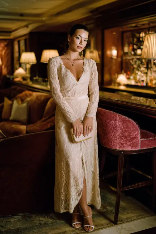 a classic floor-length long-sleeve lace gown in soft champagne ivory with a fitted silhouette, delicate floral lace detailing throughout