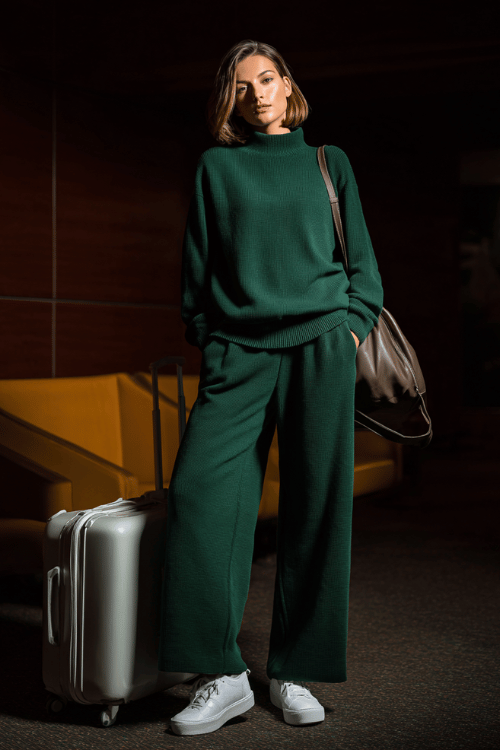 woman wearing a luxurious matching set in deep forest green an oversized mock-neck pullover and wide-leg pants in butter-soft modal fabric with memory foam white sneakers