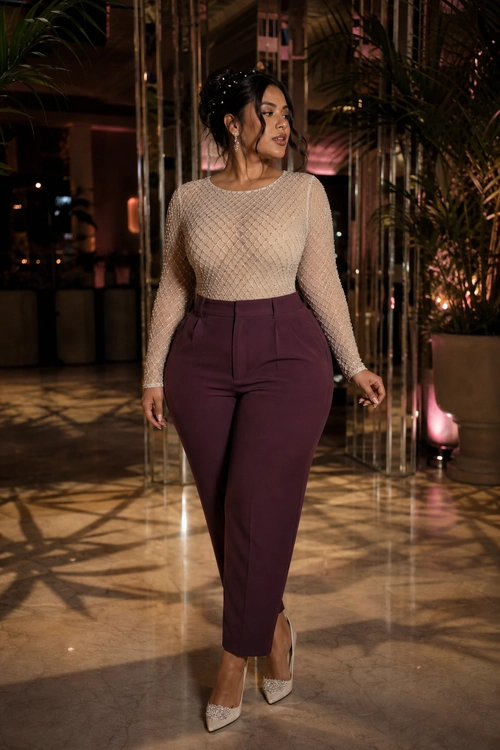 A woman wears a beige textured long-sleeve top with burgundy tailored trousers and embellished pointed-toe heels.