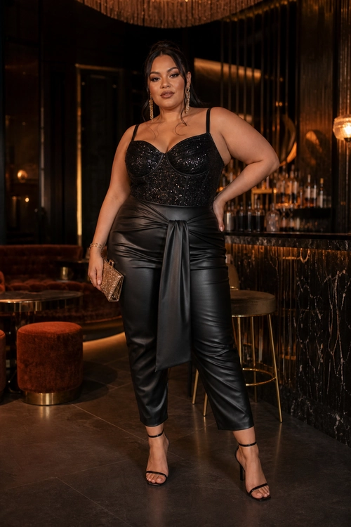 Black Corset and Trousers Evening Look A woman wears a black embellished corset top with ruched faux-leather trousers, strappy heeled sandals, drop earrings, and a metallic clutch.