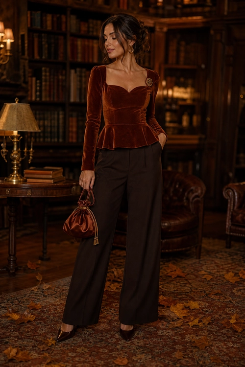A burgundy velvet peplum top styled with dark wide-leg trousers, pointed heels, and a small drawstring handbag.