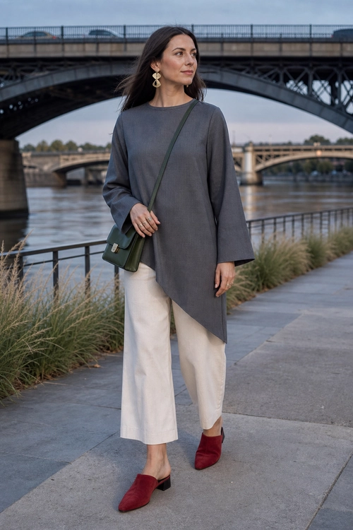 Gray Tunic and Cream Trousers Outfit A woman wears a gray asymmetrical long-sleeve tunic with cream cropped trousers, burgundy mule heels, gold drop earrings, and a green crossbody bag.