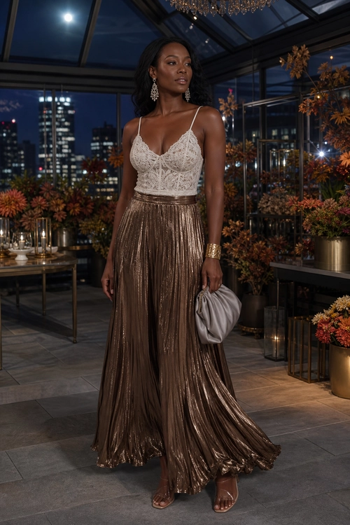 Lace Top and Metallic Pleated Skirt Woman wearing an ivory lace camisole top with a bronze metallic pleated maxi skirt, gold jewelry, and a light gray clutch.
