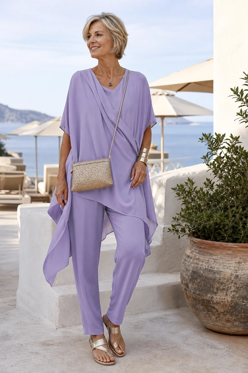 Lavender Draped Resort Outfit Woman wearing a lavender draped tunic with matching pants, metallic sandals, and a woven crossbody bag outdoors.