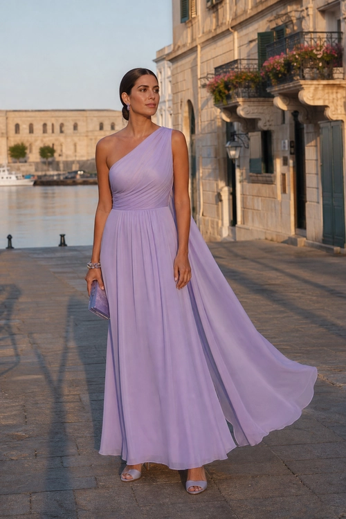 Lavender One-Shoulder Evening Dress A woman wears a flowing lavender one-shoulder floor-length dress with metallic sandals and a matching clutch by a waterfront promenade.