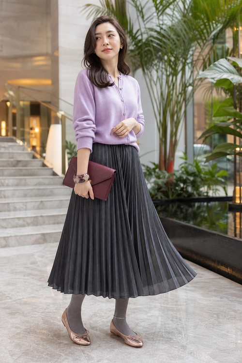 Lavender Sweater and Pleated Skirt Outfit Woman wearing a lavender long-sleeve sweater with a dark pleated midi skirt, gray tights, rose-colored shoes, and a burgundy clutch.