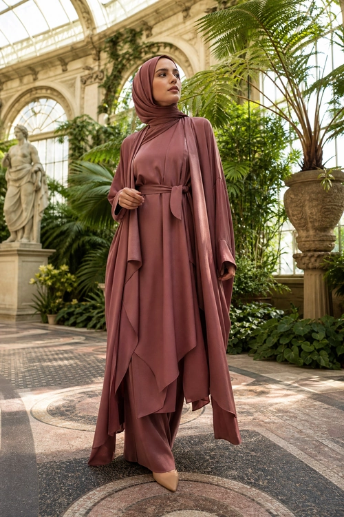 Mauve Draped Modest Outfit A woman wears a mauve hijab with a flowing draped tunic, matching wide-leg trousers, and pointed beige flats.