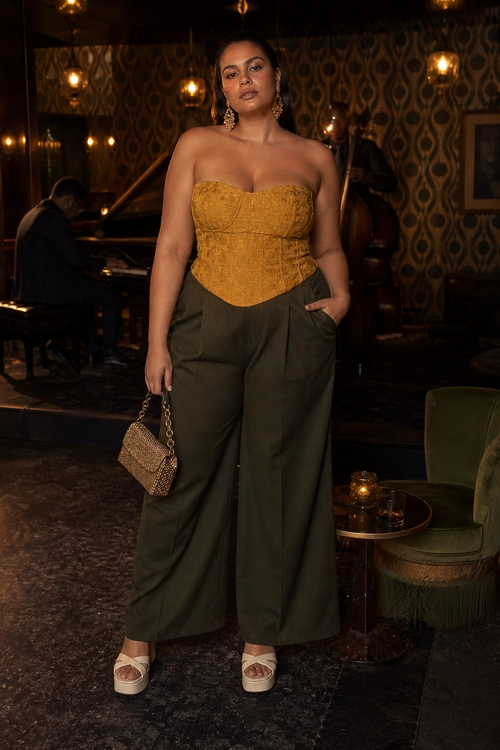 Mustard Corset and Olive Wide-Leg Outfit A strapless mustard corset top styled with olive wide-leg trousers, cream platform sandals, dangling earrings, and a small chain-handle handbag.