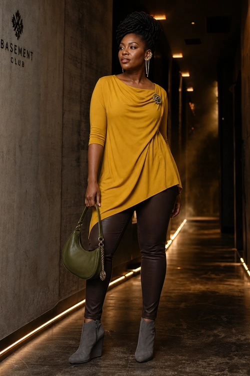 Mustard Draped Tunic Outfit A woman wears a mustard draped tunic with dark leggings, gray ankle boots, and an olive green handbag.