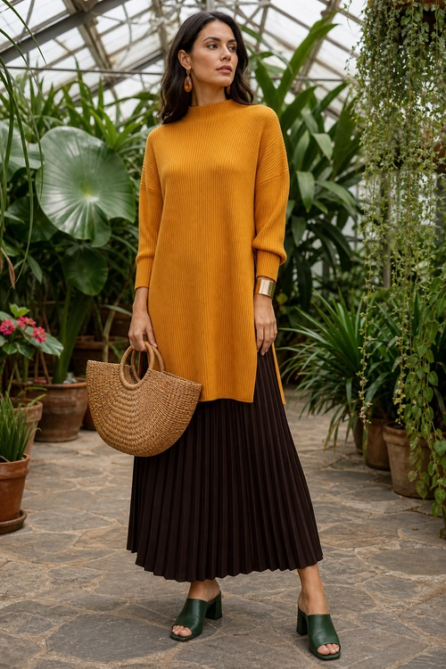 Mustard Sweater and Pleated Skirt Outfit A woman wears a mustard ribbed sweater with a dark brown pleated skirt, green heeled sandals, and a woven straw tote.