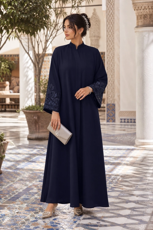 Navy Embroidered-Sleeve Abaya Look A woman wears a flowing navy abaya with embroidered sleeves, beige pointed heels, and a metallic clutch.