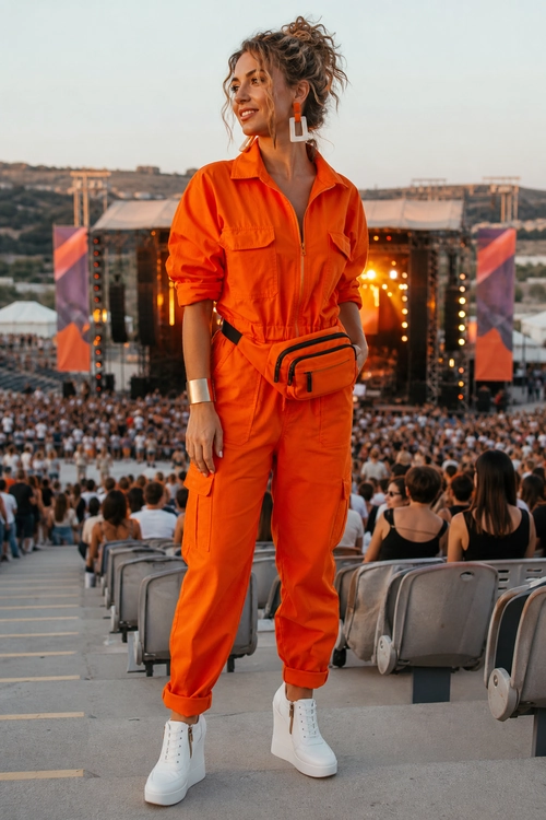 A person wears a bright orange utility jumpsuit with white high-top sneakers and an orange waist bag.