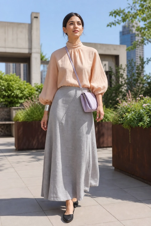 Peach Blouse and Gray Skirt Outfit A woman wears a peach high-neck blouse with puff sleeves, a long gray skirt, a lavender crossbody bag, and black flat shoes.