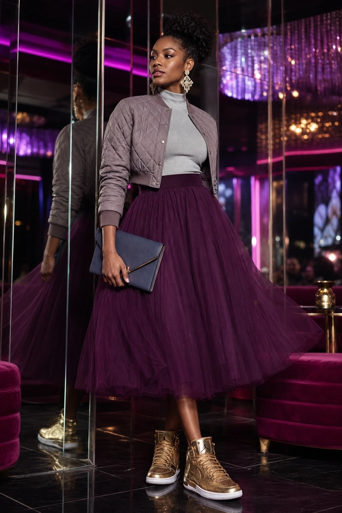 Quilted Jacket and Plum Tulle Skirt Outfit A woman wears a gray quilted jacket over a gray turtleneck with a plum tulle midi skirt, clutch, statement earrings, and metallic high-top sneakers.