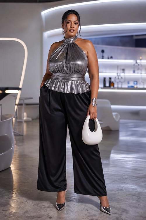 A woman wears a metallic silver halter peplum top with black wide-leg trousers, pointed-toe heels, and a white handbag.