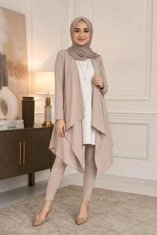 A woman wearing a taupe hijab, flowing long cardigan, white tunic, fitted taupe pants, pointed flats, and a delicate necklace.
