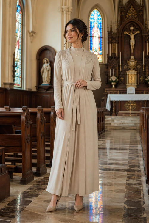 Woman wearing a long beige tie-waist dress with lace detailing and pointed nude heels.