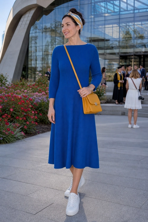 A woman wears a royal blue ribbed midi dress with white sneakers, a mustard yellow crossbody bag, and a patterned headband.