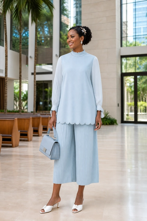 Light Blue Pleated Tunic Outfit A woman wears a pale blue long-sleeve tunic with a scalloped hem, pleated wide-leg culottes, white heeled mules, and a matching handbag.