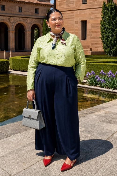 Lime Blouse and Navy Wide-Leg Trousers A polished outfit featuring a lime green textured blouse, navy wide-leg trousers, a patterned neck scarf, a gray structured handbag, and red pointed shoes.