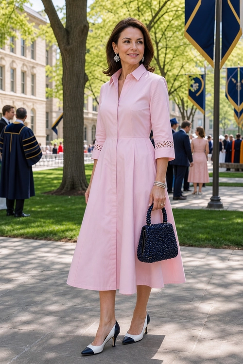 A woman wears a pale pink shirt dress with lace-trimmed sleeves, black-and-white pointed heels, and a black beaded handbag outdoors.